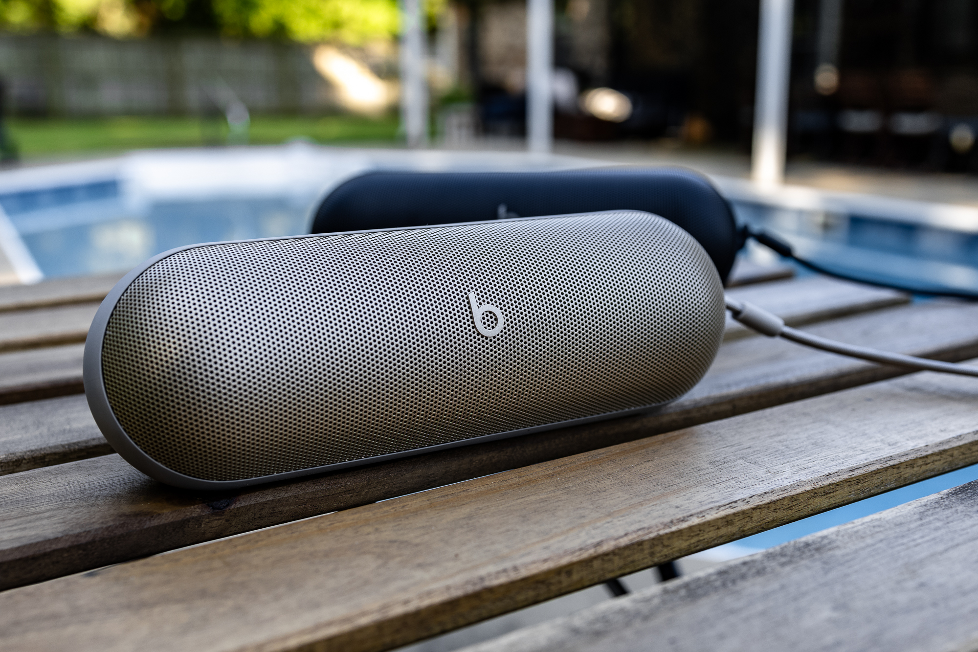 The 2024 model of Beats Pill Bluetooth speaker on a table near a pool.