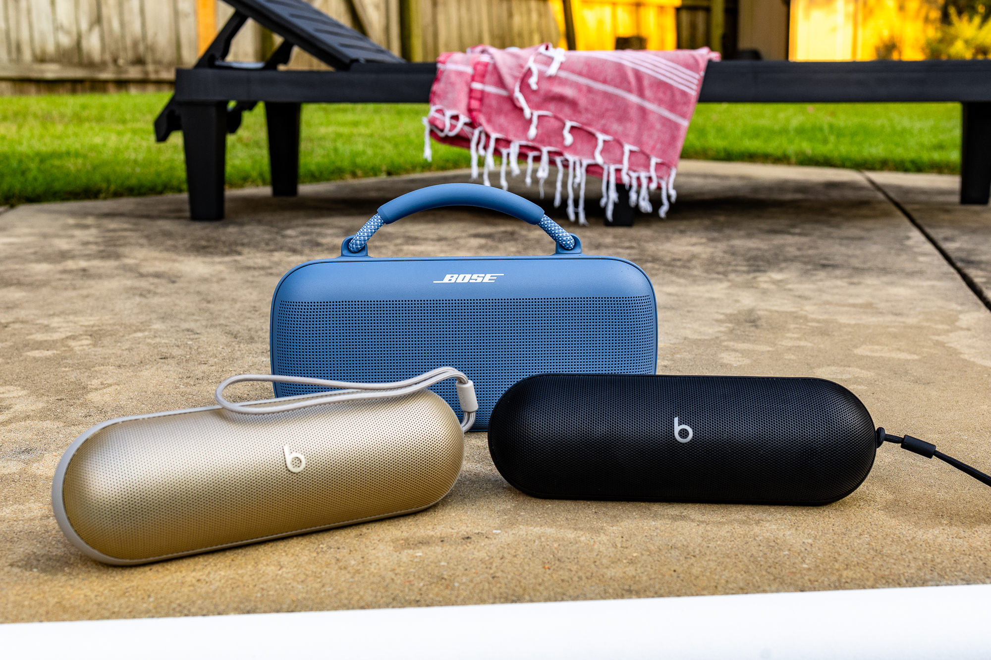 Os alto-falantes Beats Pill dourados e pretos na frente do Bose SoundLink Max.