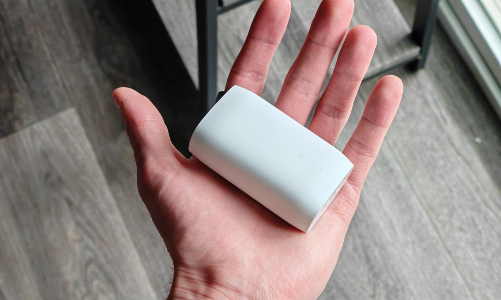 Someone holding a white Belkin charger.