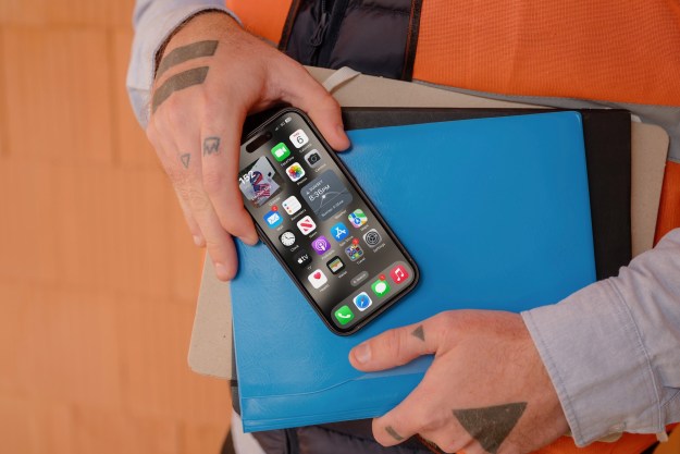 An iPhone showing the home screen in someone's hand.