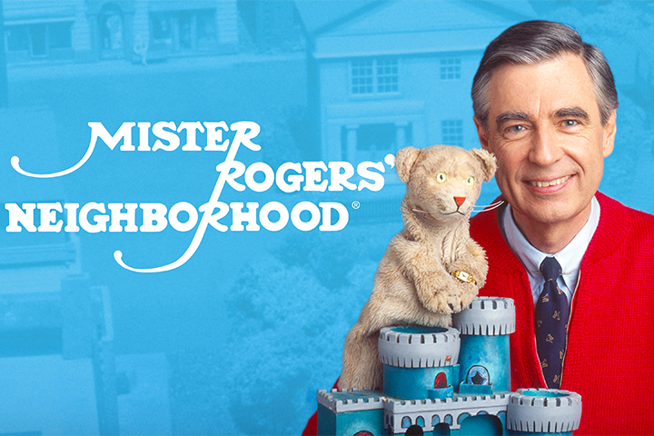 Promotional poster for Mister Rogers' Neighborhood featuring Fred Rogers pinch a puppet smiling.