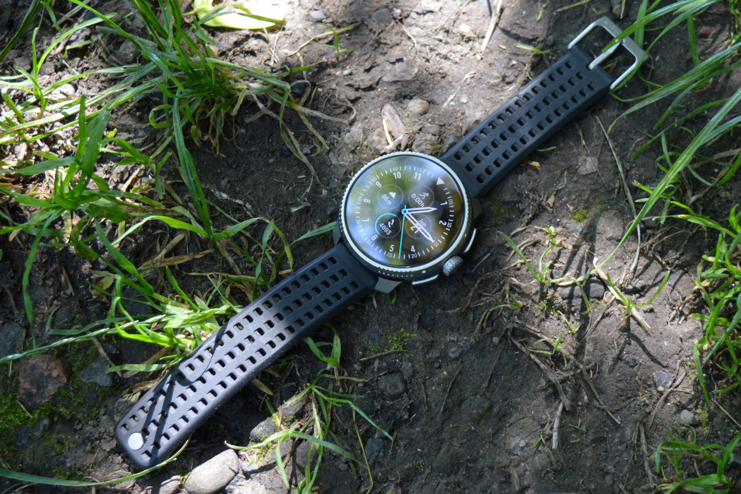 The Suunto Race laid on a forest floor.