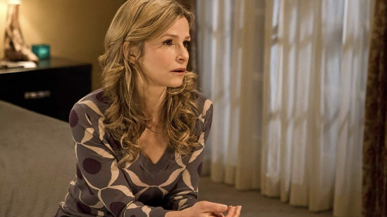 Kyra Sedgwick in The Closer sitting on a bed looking pensive. 