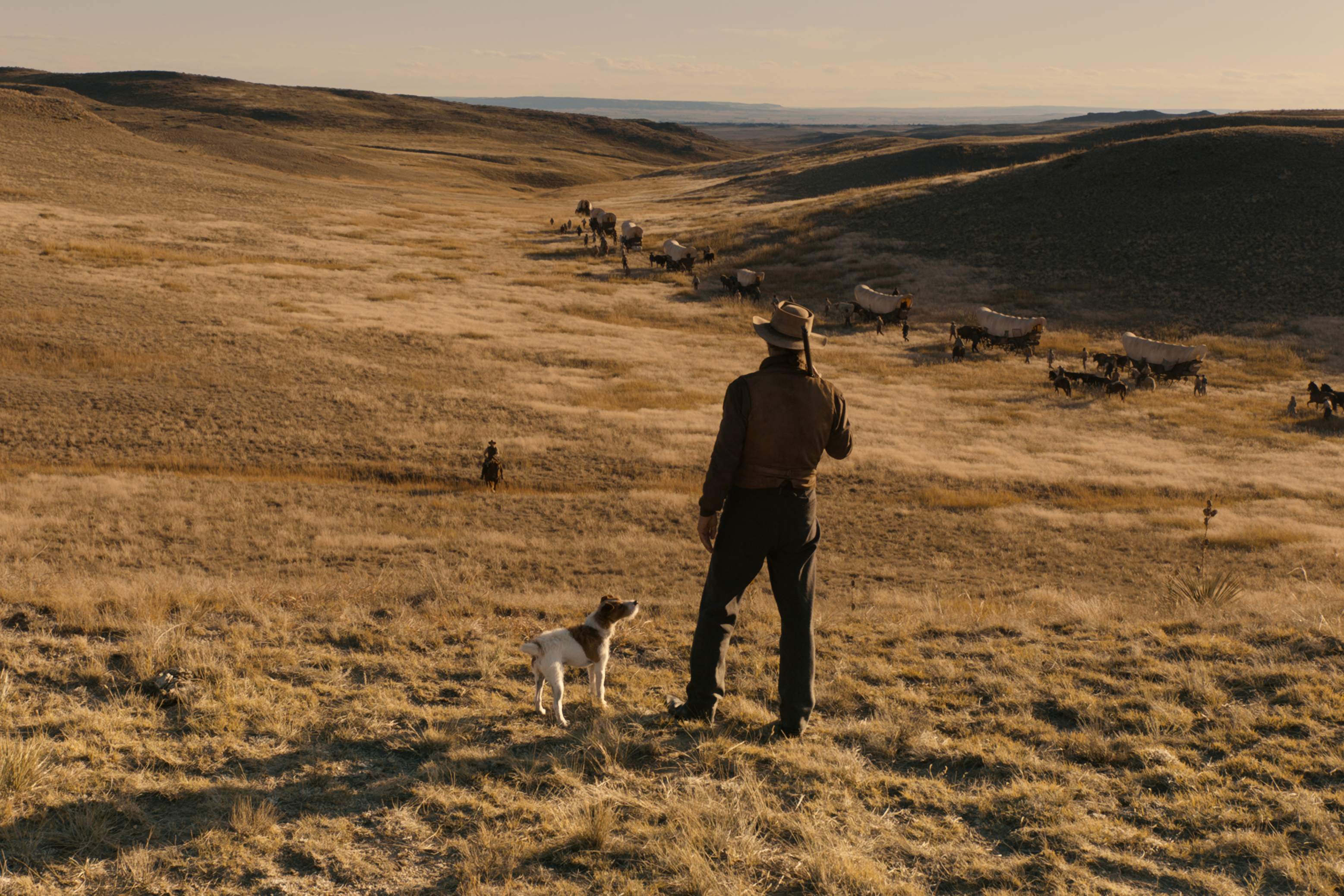 A cowboy stands next to a dog in The Ballad of Buster Scruggs.