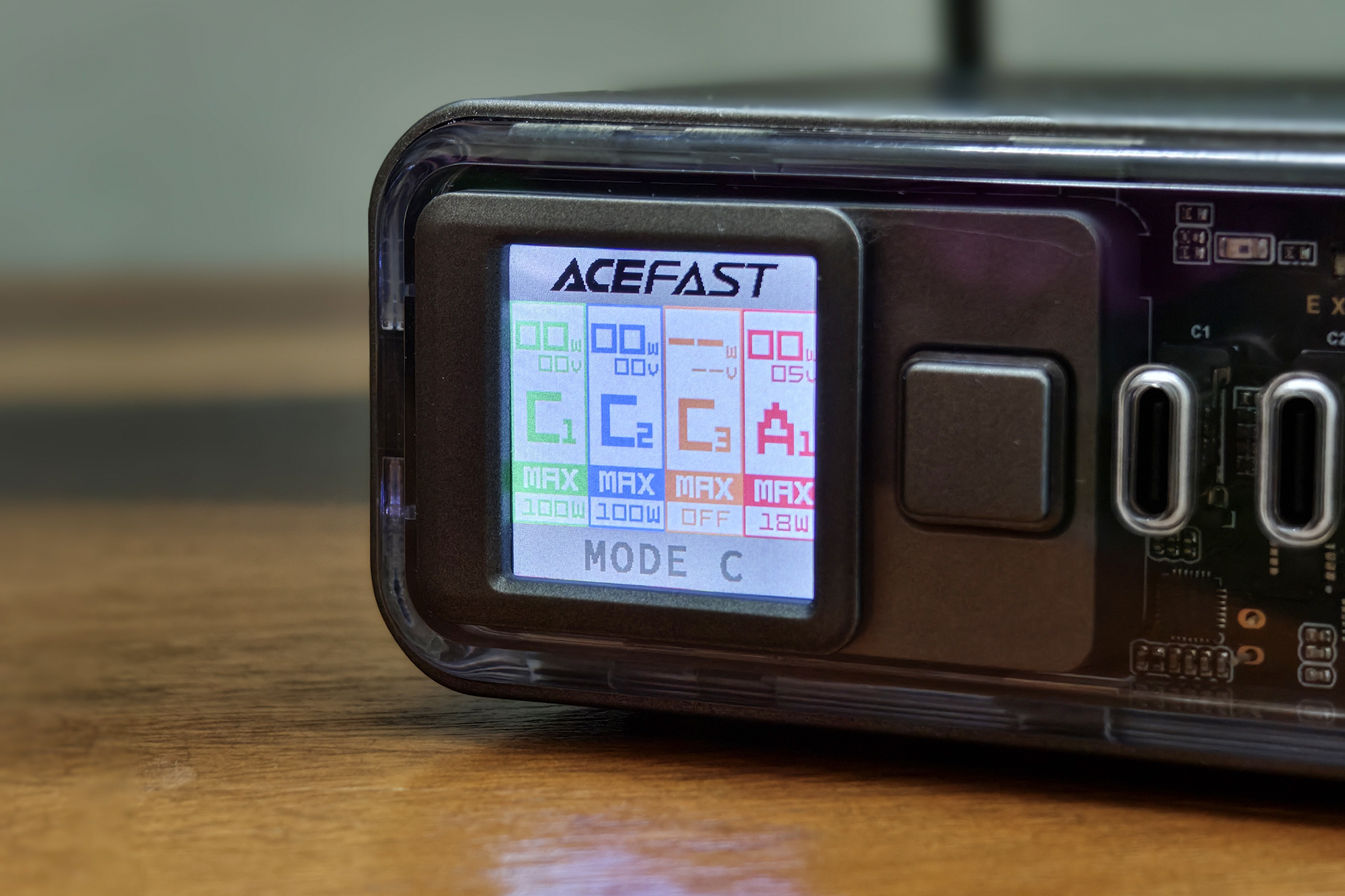 Acefast Z4 218W 快速充电器上的 1.4 英寸 LCD TFT 显示屏，显示屏和透明前面板保留在木质表面上。