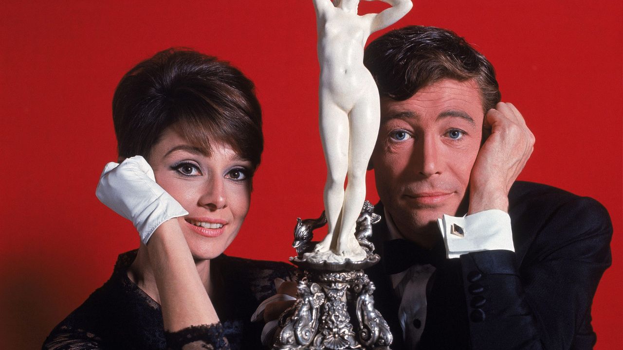 Audrey Hepburn e Peter O'Toole sorrindo e olhando para a câmera em uma foto promocional de How to Steal a Million,