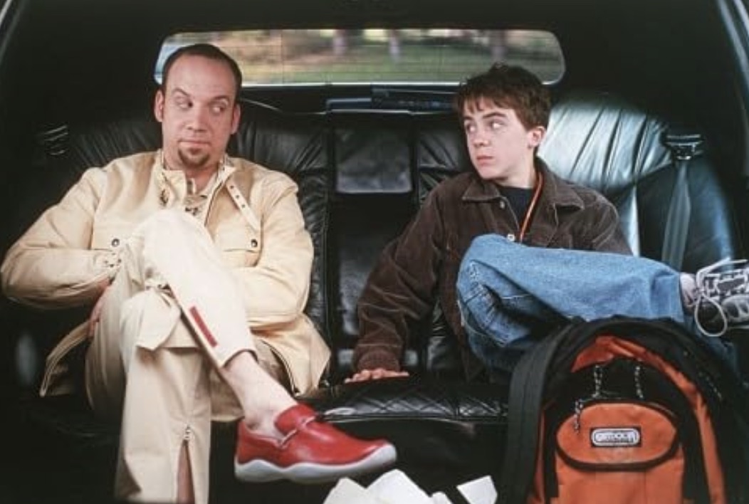 A man and boy sit next to each other in a limo.