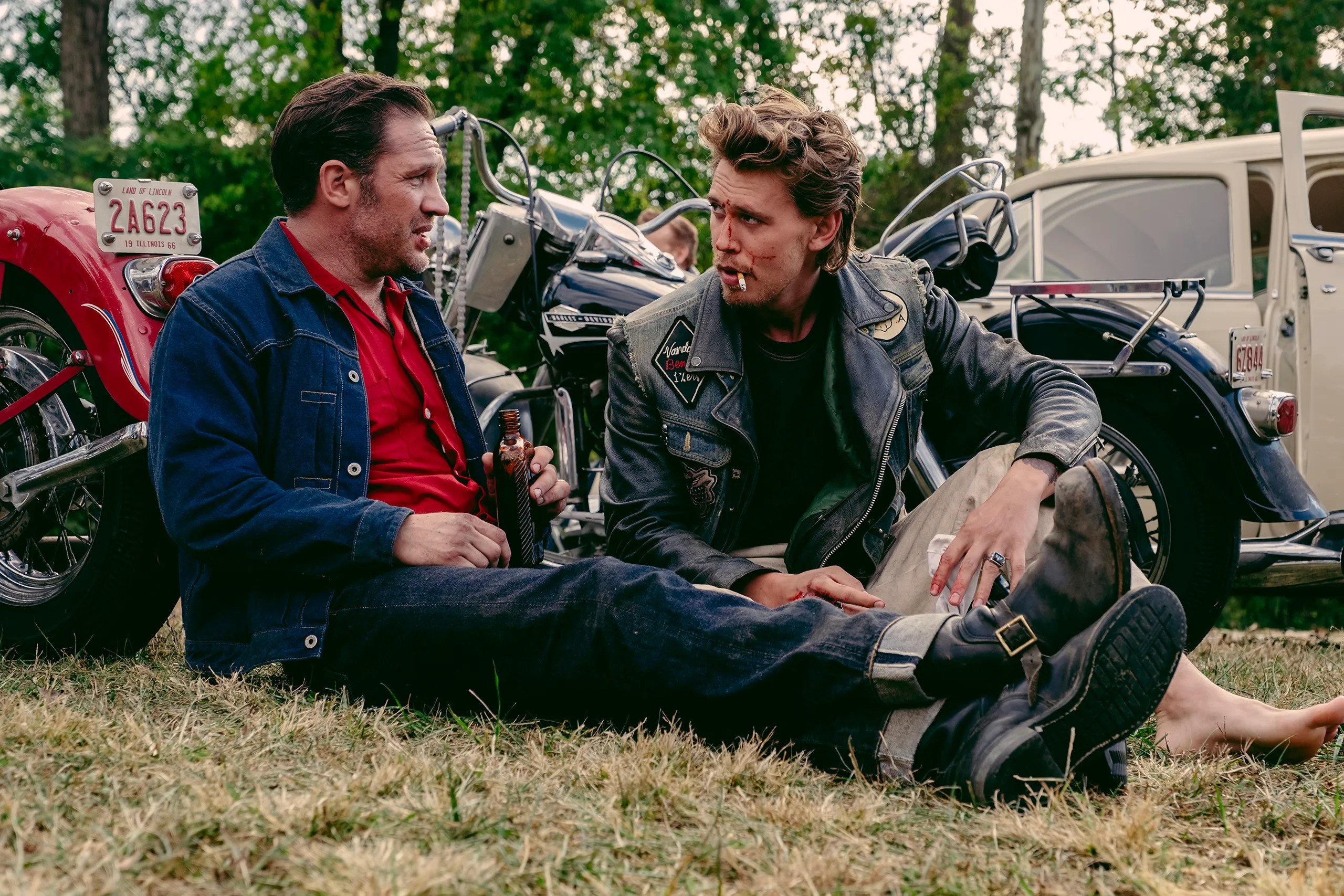 Two men sit on the ground in The Bikeriders.