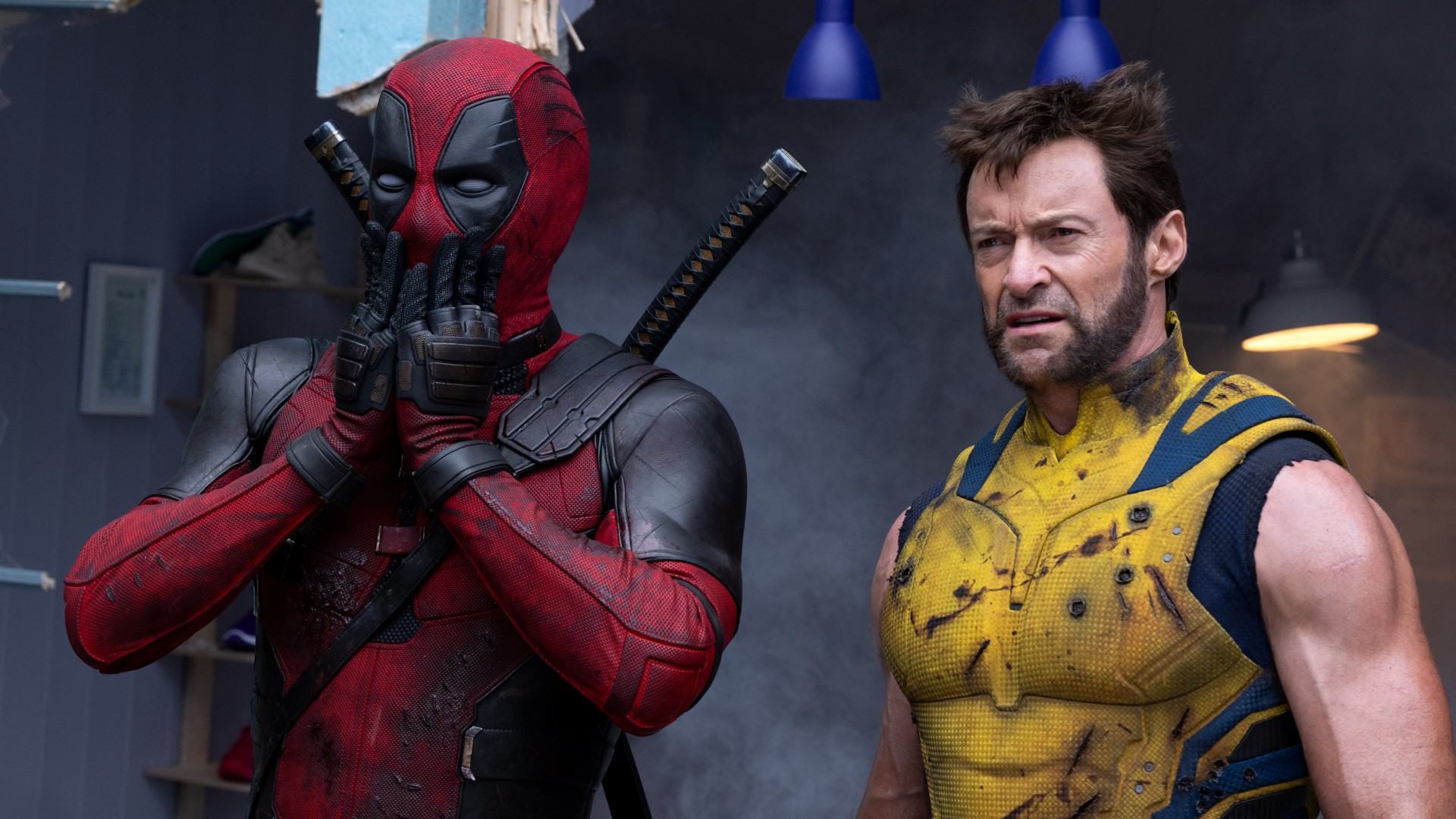 A masked Ryan Reynolds covers his mouth as Hugh Jackman glowers in a still from the movie "Deadpool & Wolverine."