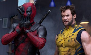 A masked Ryan Reynolds covers his mouth as Hugh Jackman glowers in a still from the movie "Deadpool & Wolverine."