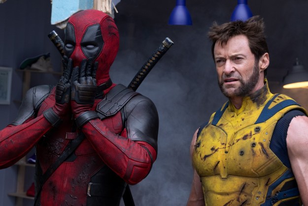 A masked Ryan Reynolds covers his mouth as Hugh Jackman glowers in a still from the movie "Deadpool & Wolverine."