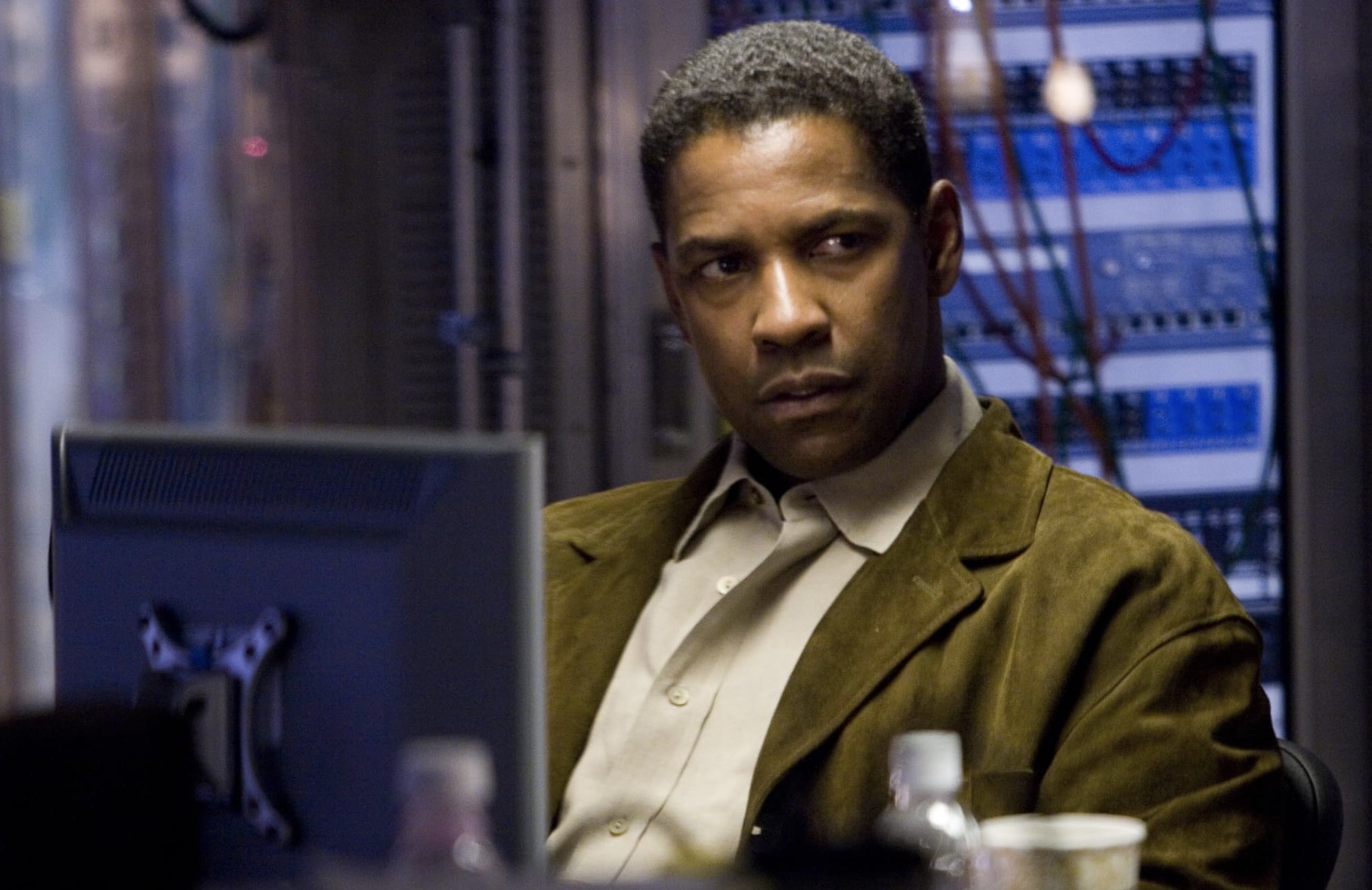 Denzel Washington se sienta en un escritorio y mira fijamente.