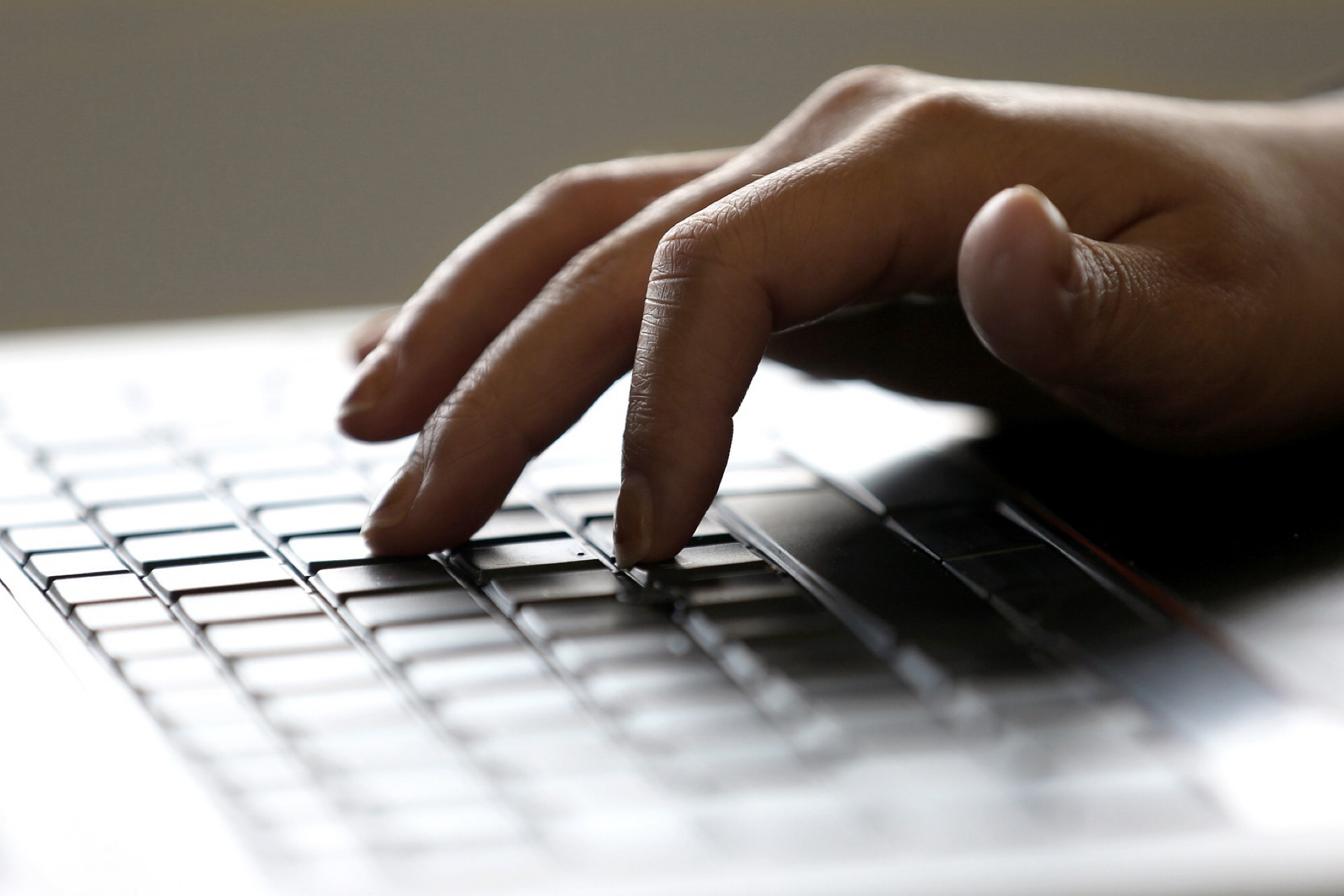 Hand typing on a laptop keyboard.