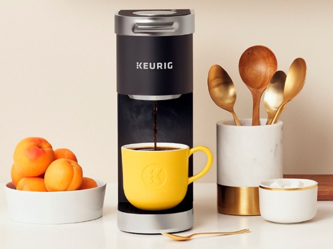 A Keurig K-Mini Plus Single Serve K-Cup Pod Coffee Maker next to coffee cream accessories.