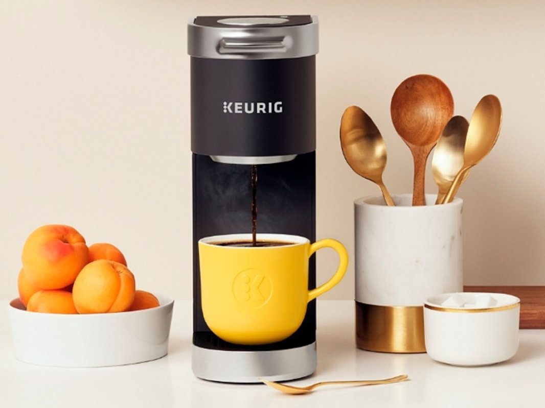 Una cafetera Keurig K-Mini Plus Single Serve K-Cup Pod junto a accesorios para crema de café.