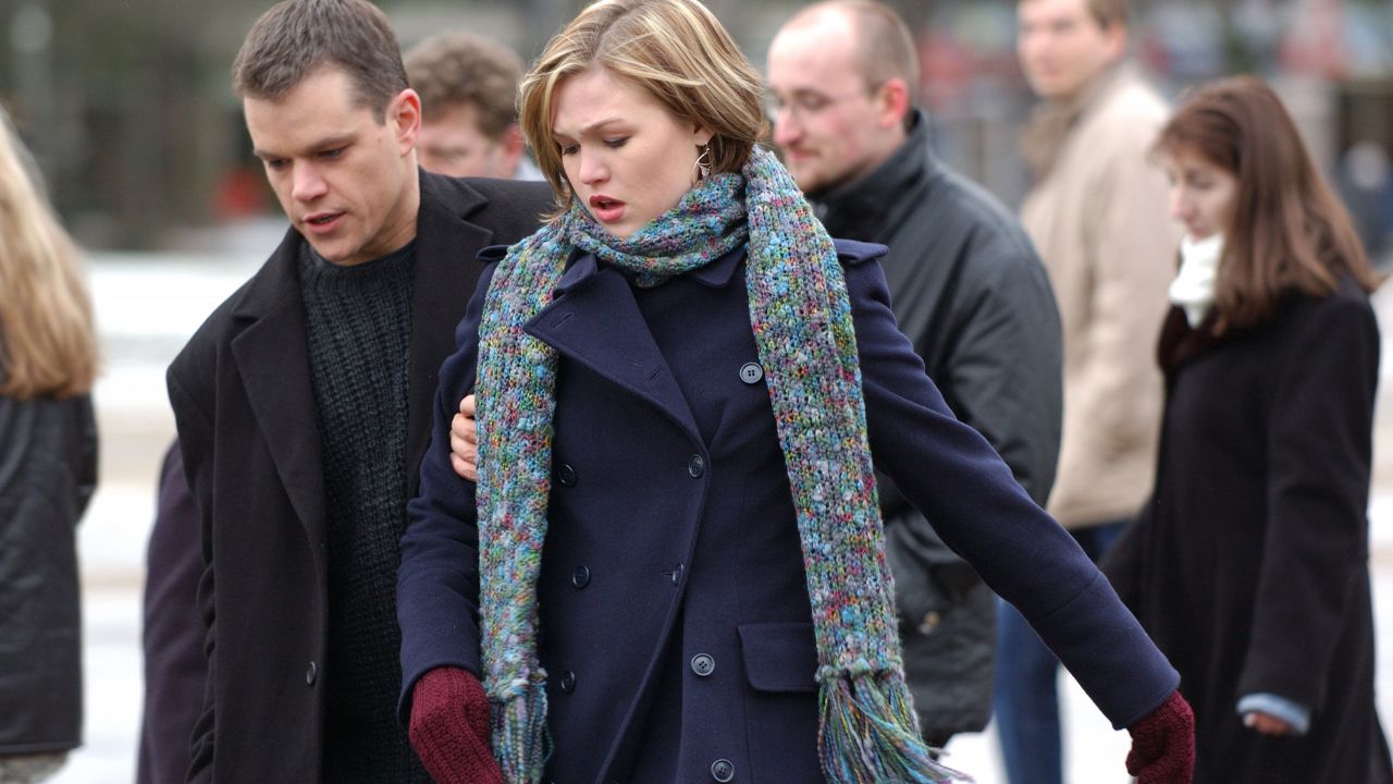 Matt Damon como Jason Bourne guiando a Julia Stiles como Nicky a través de una calle llena de gente en The Bourne Supremacy.