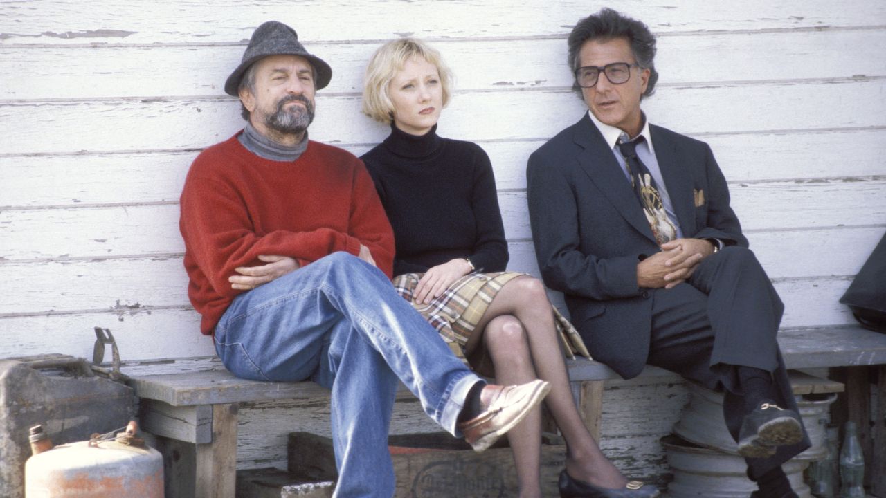 Robert De Niro, Anne Heche e Dustin Hoffman como Conrad, Winifred e Stanley sentados em um banco no filme Wag the Dog.