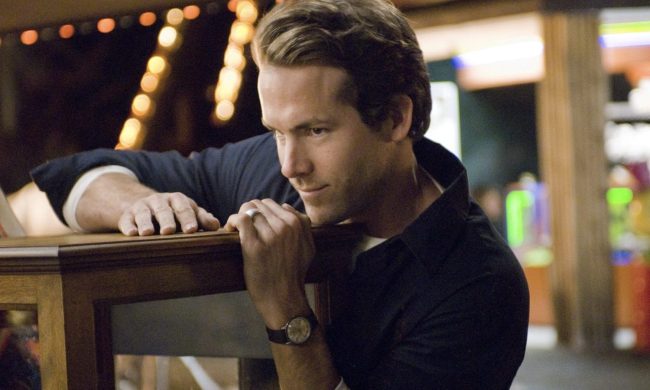 Ryan Reynolds leans over a counter and smirks.