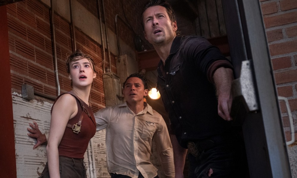 Daisy Edgar-Jones, Anthony Ramos, and Glen Powell stare offscreen at a tornado, probably, in a still from the movie Twisters.