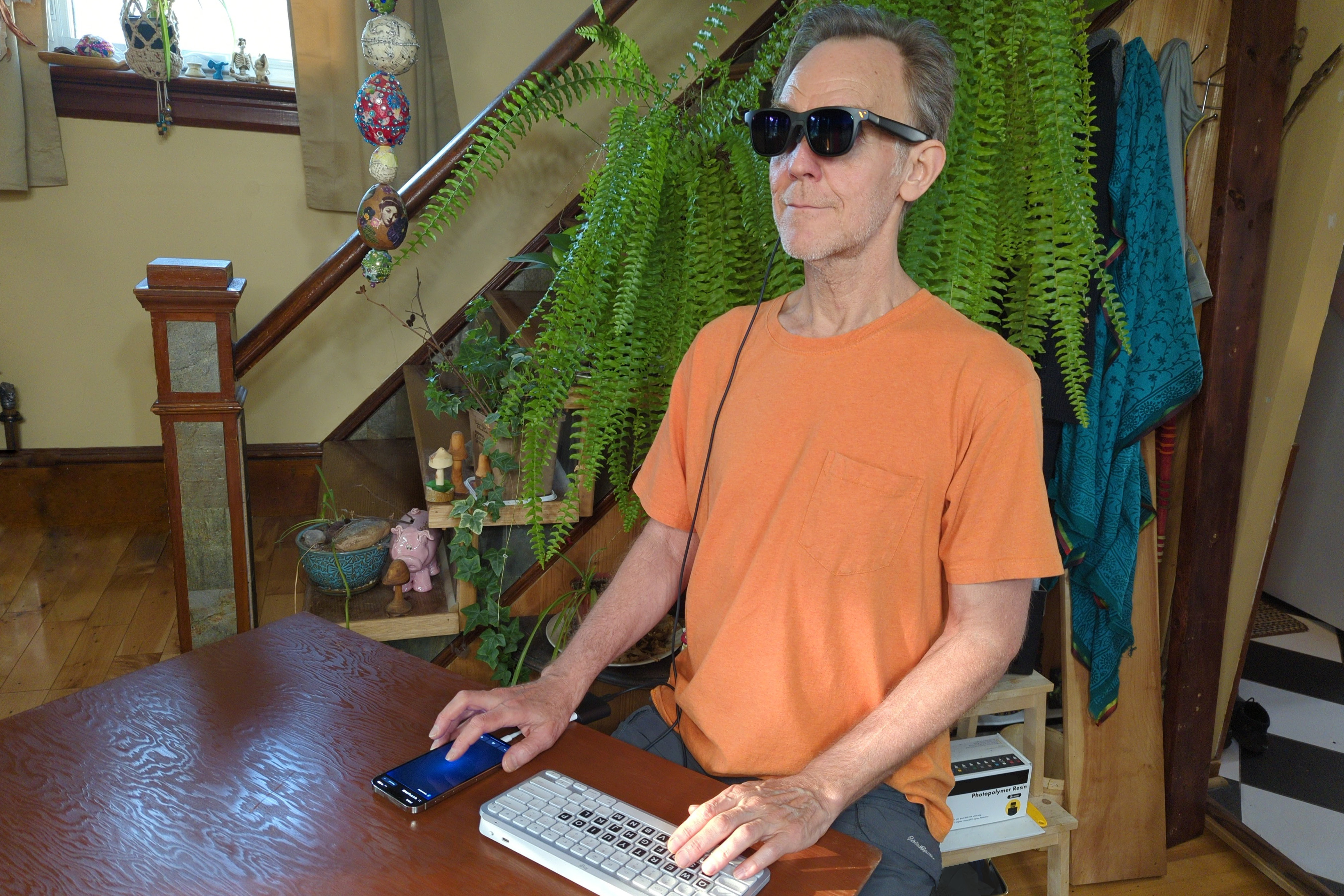 Alan Truly wears Viture Pro smart glasses while working with an iPhone and Bluetooth keyboard.