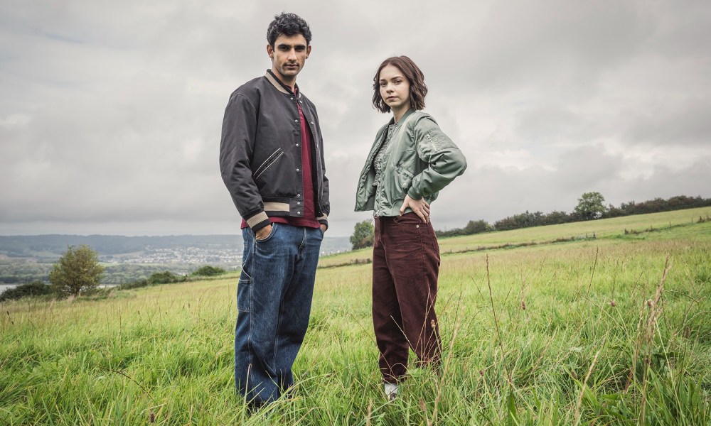 Two people stand in a field in A Good Girl's Guide to Murder.