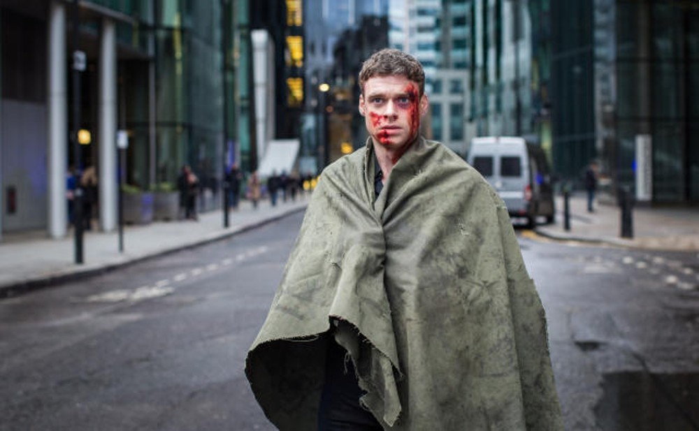 A bloody man stands in a street in Bodyguard.