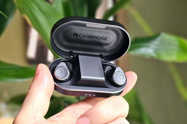 Cambridge Audio Melomania M100 in charging case, lid open, held in hand.