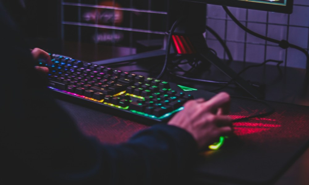 Gaming on PC at desk with RGB lighting.