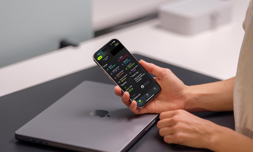 Person holding a phone that shows the Summary page in Apple Fitness in iOS 18.