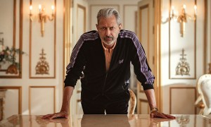 Jeff Goldblum looking straight ahead leaning over a counter with both hands on it in a scene from Kaos on Netflix.