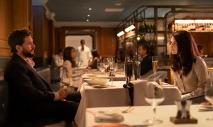 A man and woman sit across from each other at a table.