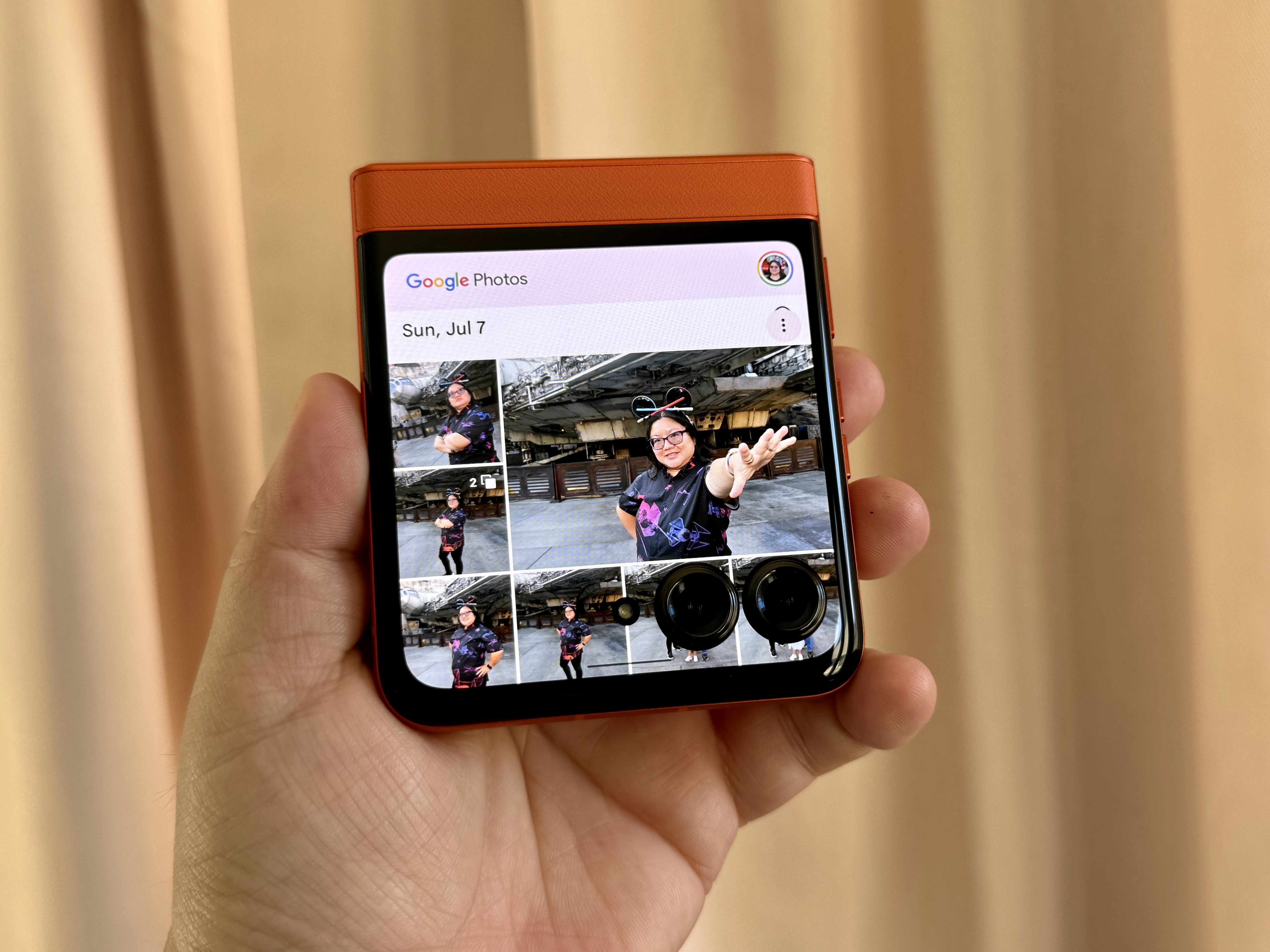 Motorola Razr 2024 in Spritz Orange in hand showing Google Photos on display.