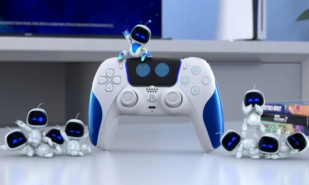 The Astro bot sitting on top of the Astro Bot DualSense controller, which is a white controller with blue handles. The middle button also has eyes that look like Astro's.