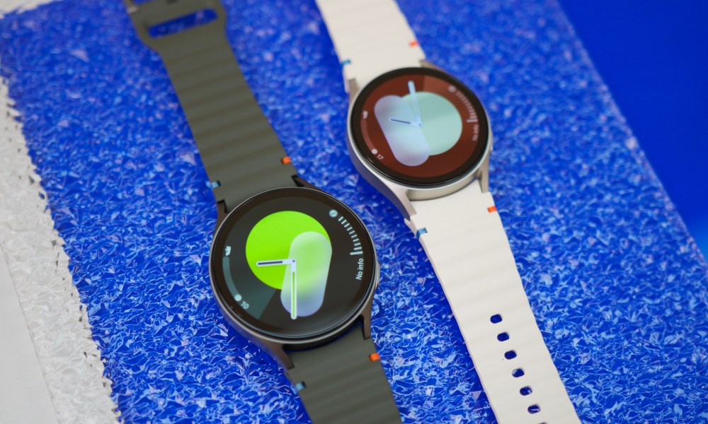 Two Samsung Galaxy Watch 7 smartwatches laying next to each other on a table.