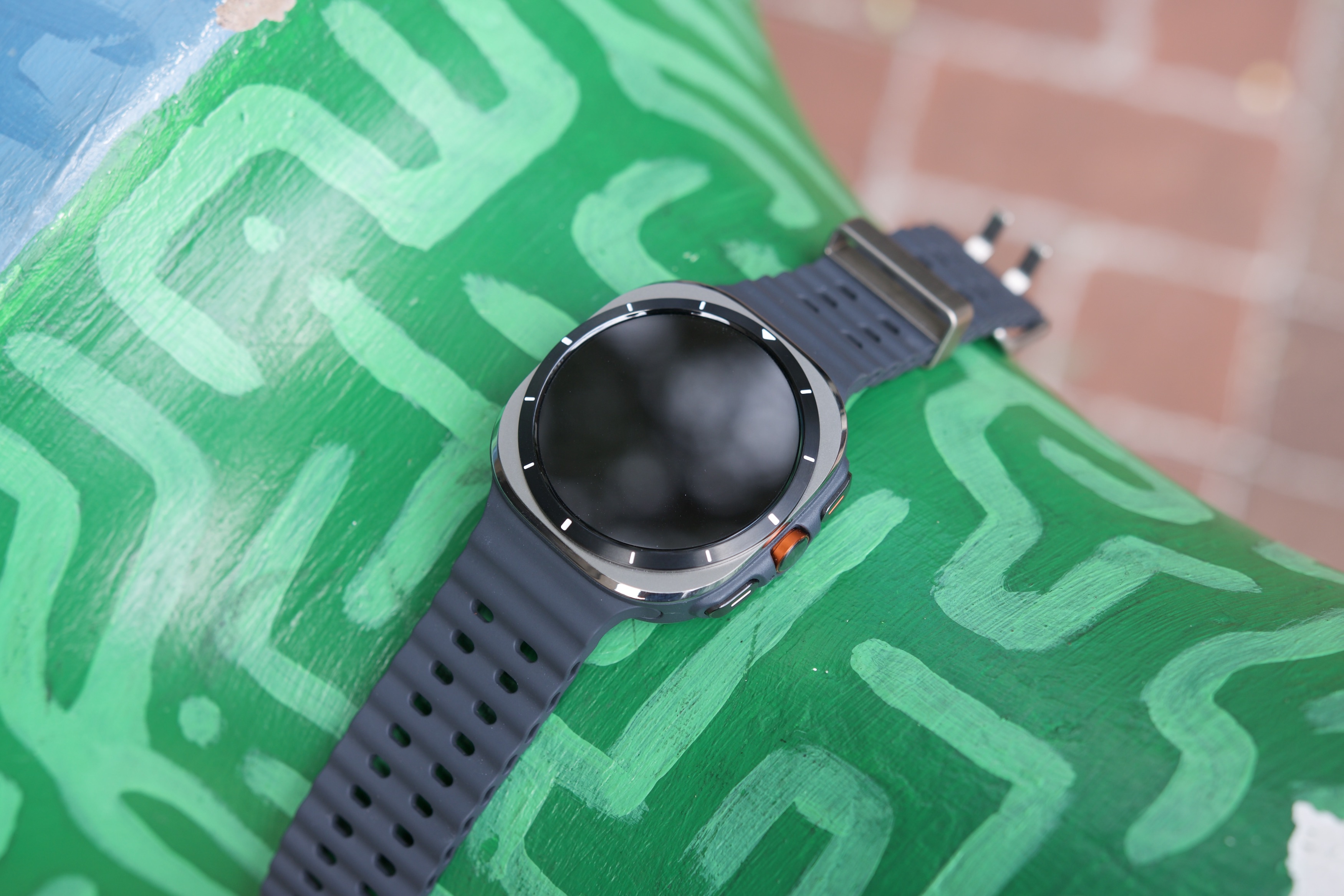 The Samsung Galaxy Watch Ultra laying on a green sculpture.