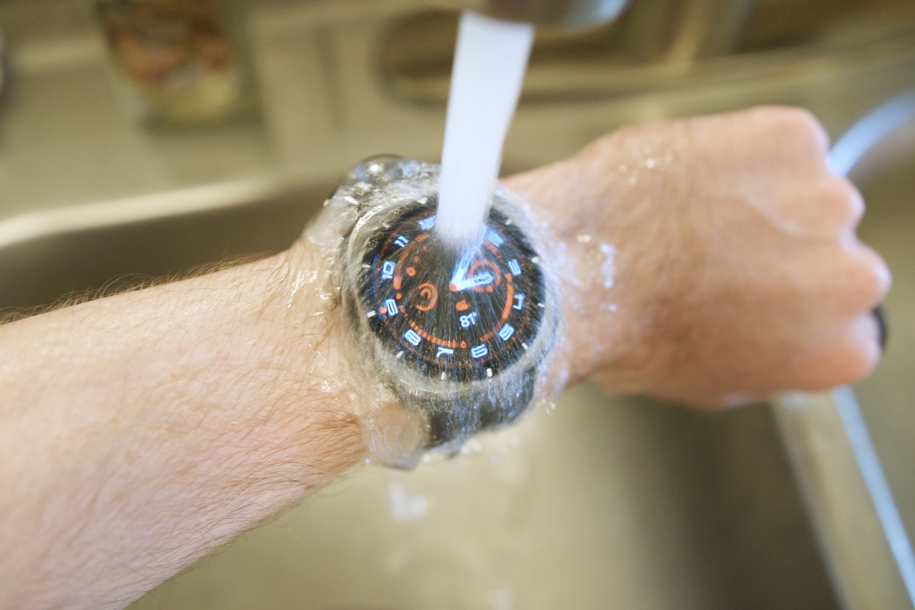 The Samsung Galaxy Watch Ultra being held under a water faucet.