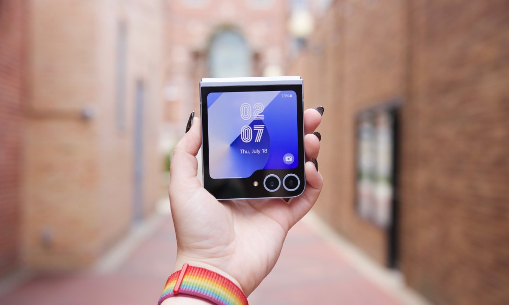 Someone holding the Samsung Galaxy Z Flip 6, showing the cover screen turned on.