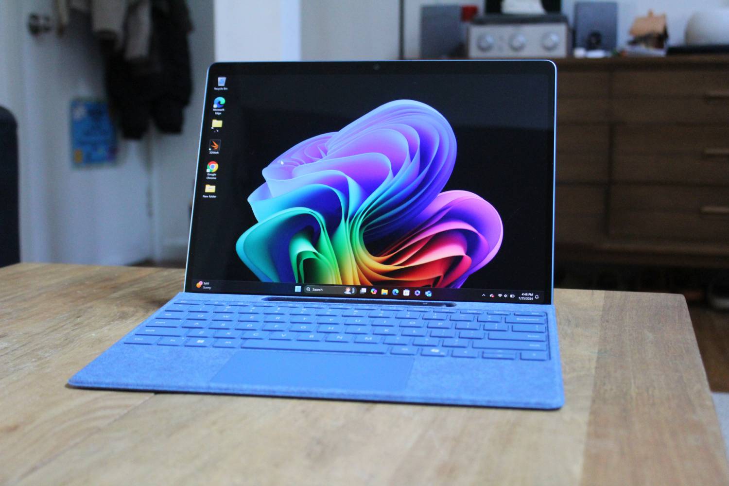 Surface Pro 11 dengan keyboard yang terpasang di atas meja kayu.