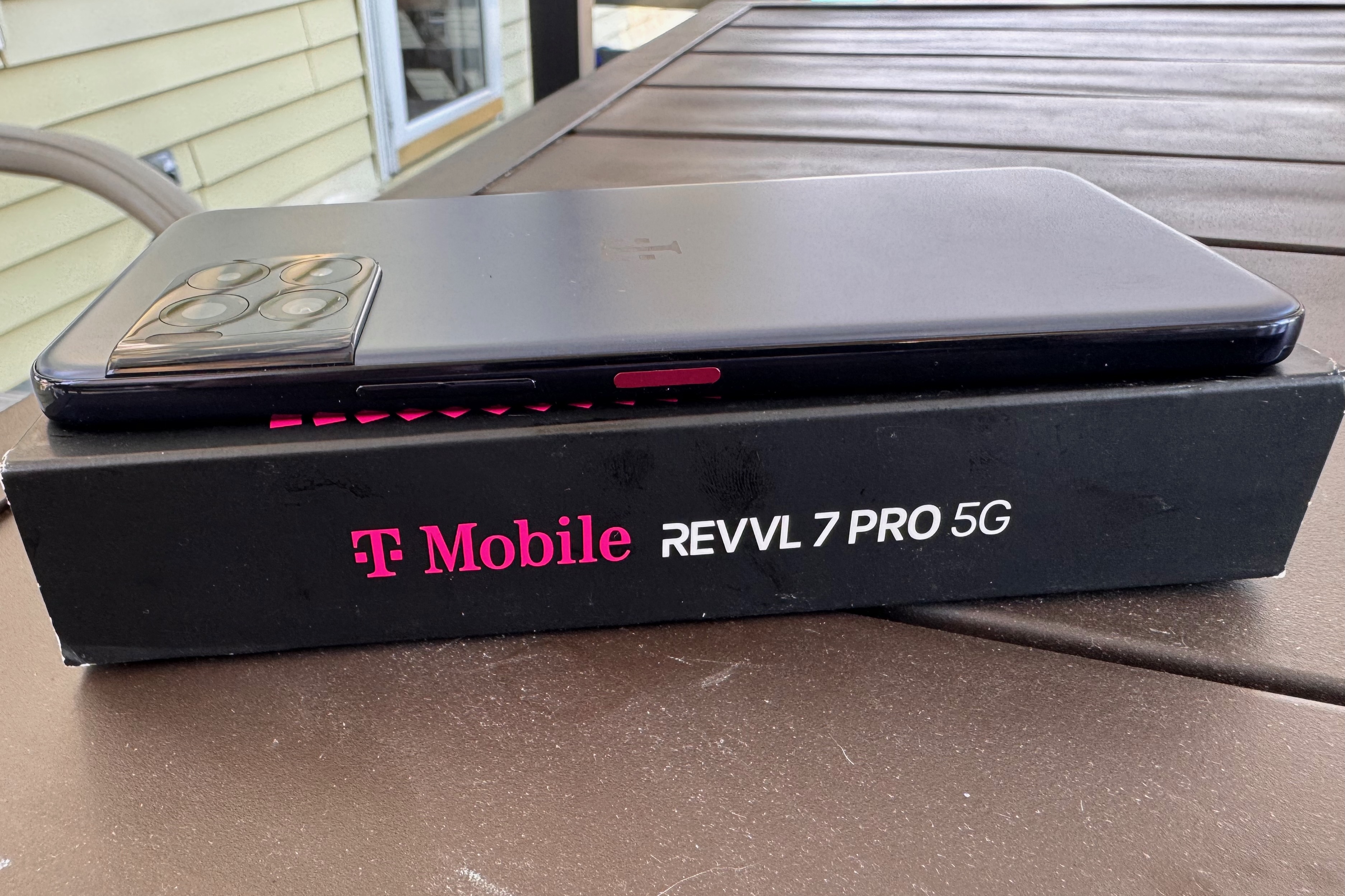 O telefone T-Mobile REVVL 7Pro 5G fica voltado para baixo em cima de sua caixa.