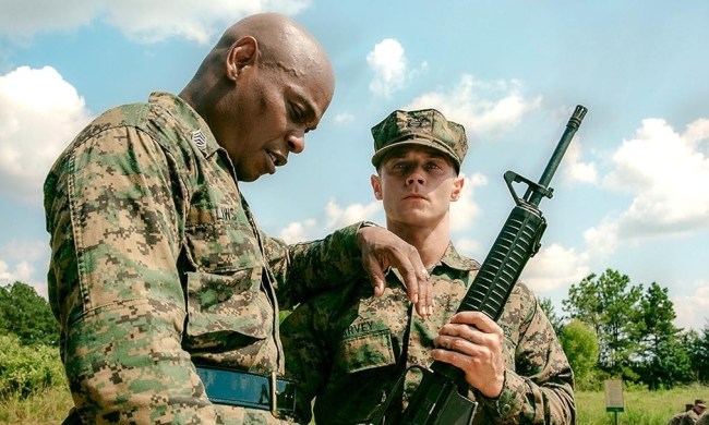 A man leans on a man with a gun in The Inspection.