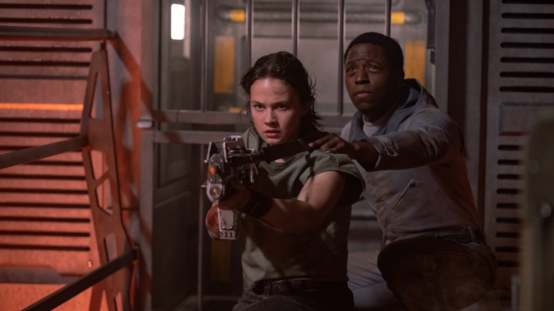 Cailee Spaeny aponta uma arma enquanto David Jonsson está atrás dela em uma foto do filme Alien: Romulus.