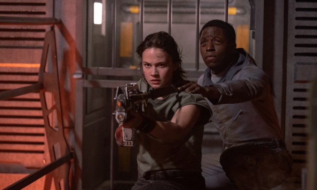 Cailee Spaeny aims a gun as David Jonsson stands behind her in a still from the movie Alien: Romulus.