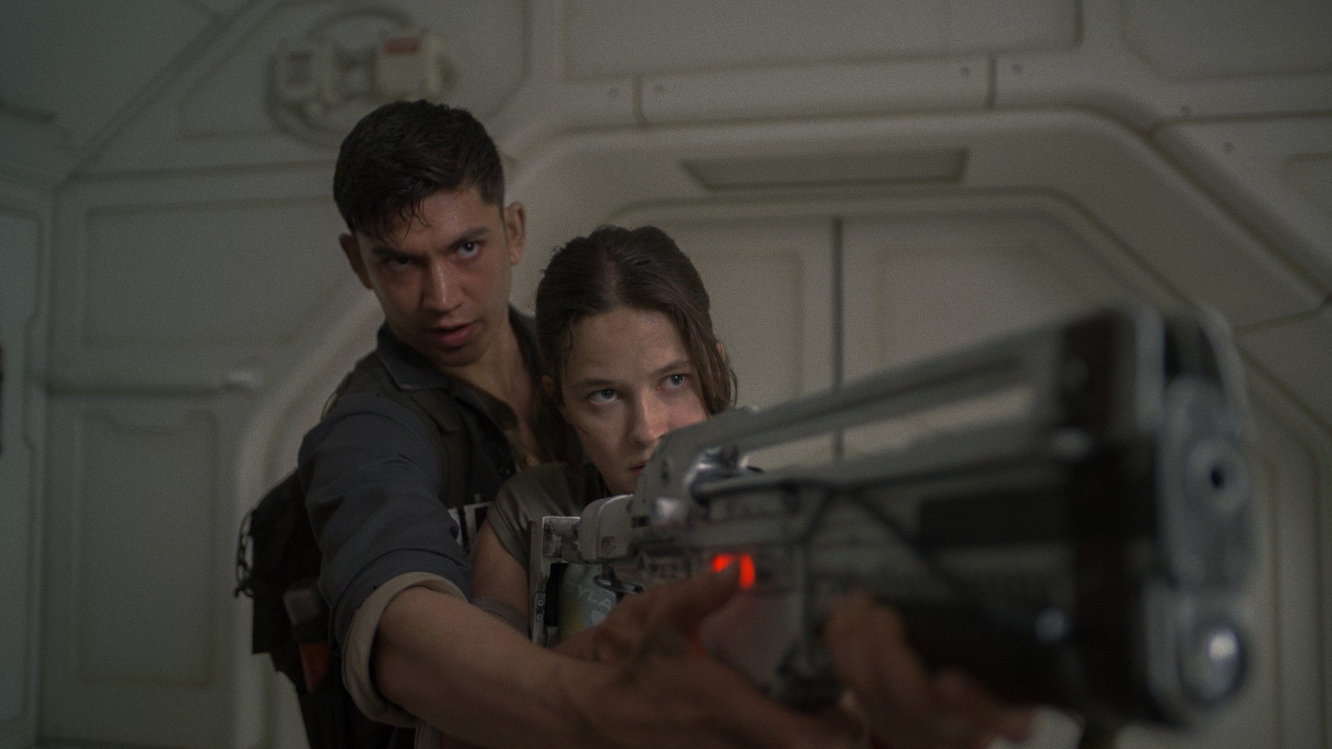 Archie Renaux shows Cailee Spaeny how to use a pulse rifle in a still from the movie Alien: Romulus.