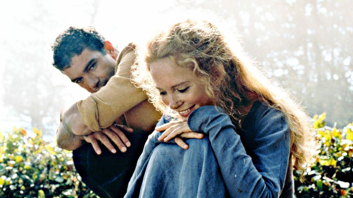 Antonio Banderas and Maria Bonnevie as Ahman ibn Fadlan and Olga smiling while sitting on the grass in The 13th Warrior.