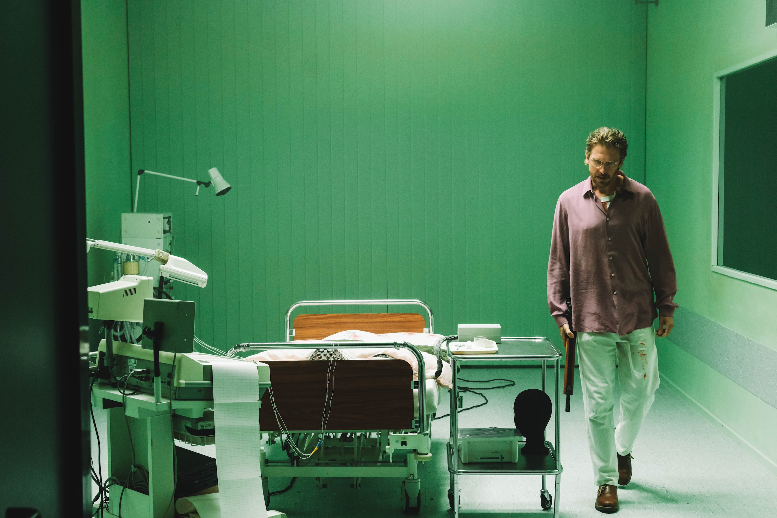 Dan Stevens segura uma arma em um quarto de hospital em Cuckoo.