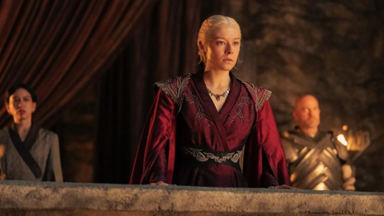 Emma D'arcy as Rhaneyra Targaryen standing on balcony with two people behind her in House of the Dragon.