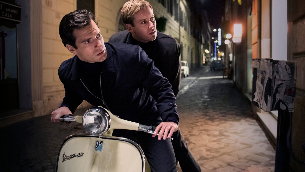 Henry Cavill e Armie Hammer como Napoleon Solo e Ilya Kuryakin em uma Vespa olhando para a esquerda em The Man From UNCLE.