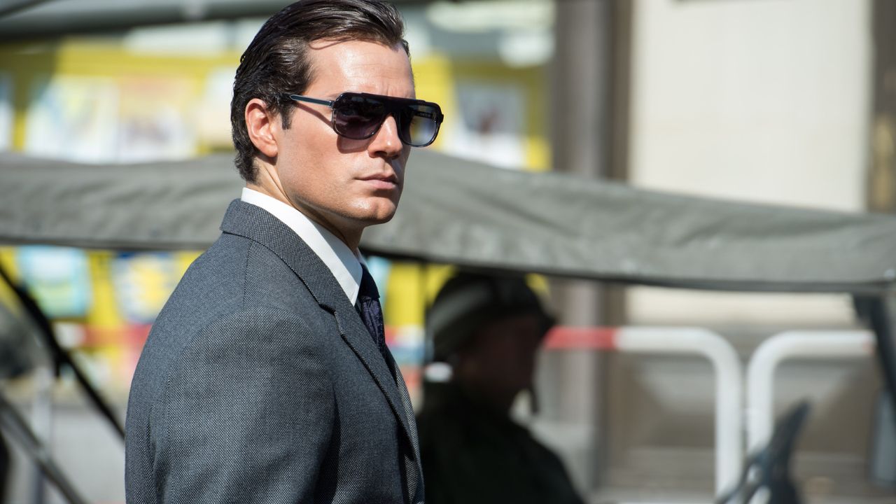 Henry Cavill como Napoleon Solo usando óculos escuros e olhando para a direita em The Man From UNCLE.