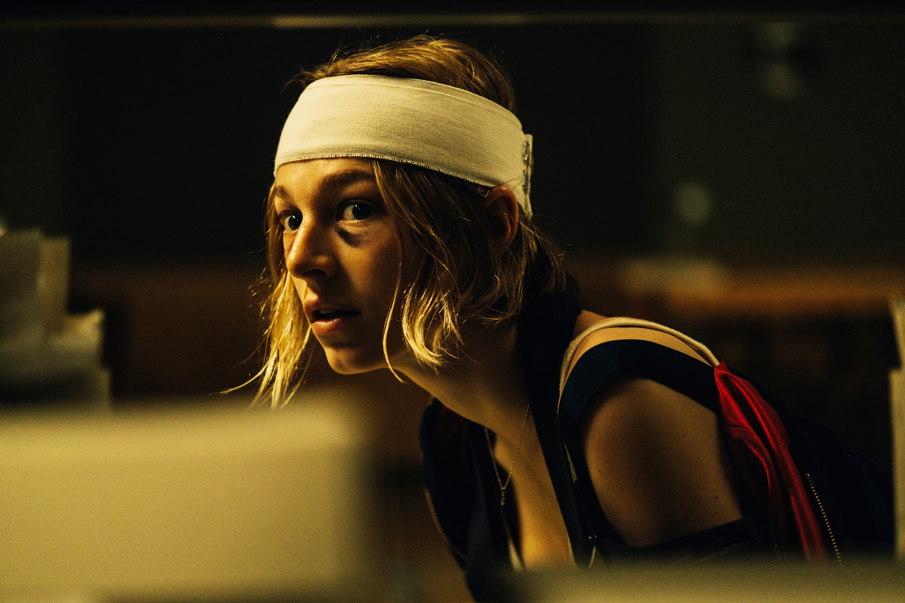 Hunter Schafer s'accroupit avec un bandage enroulé autour de la tête dans Cuckoo.