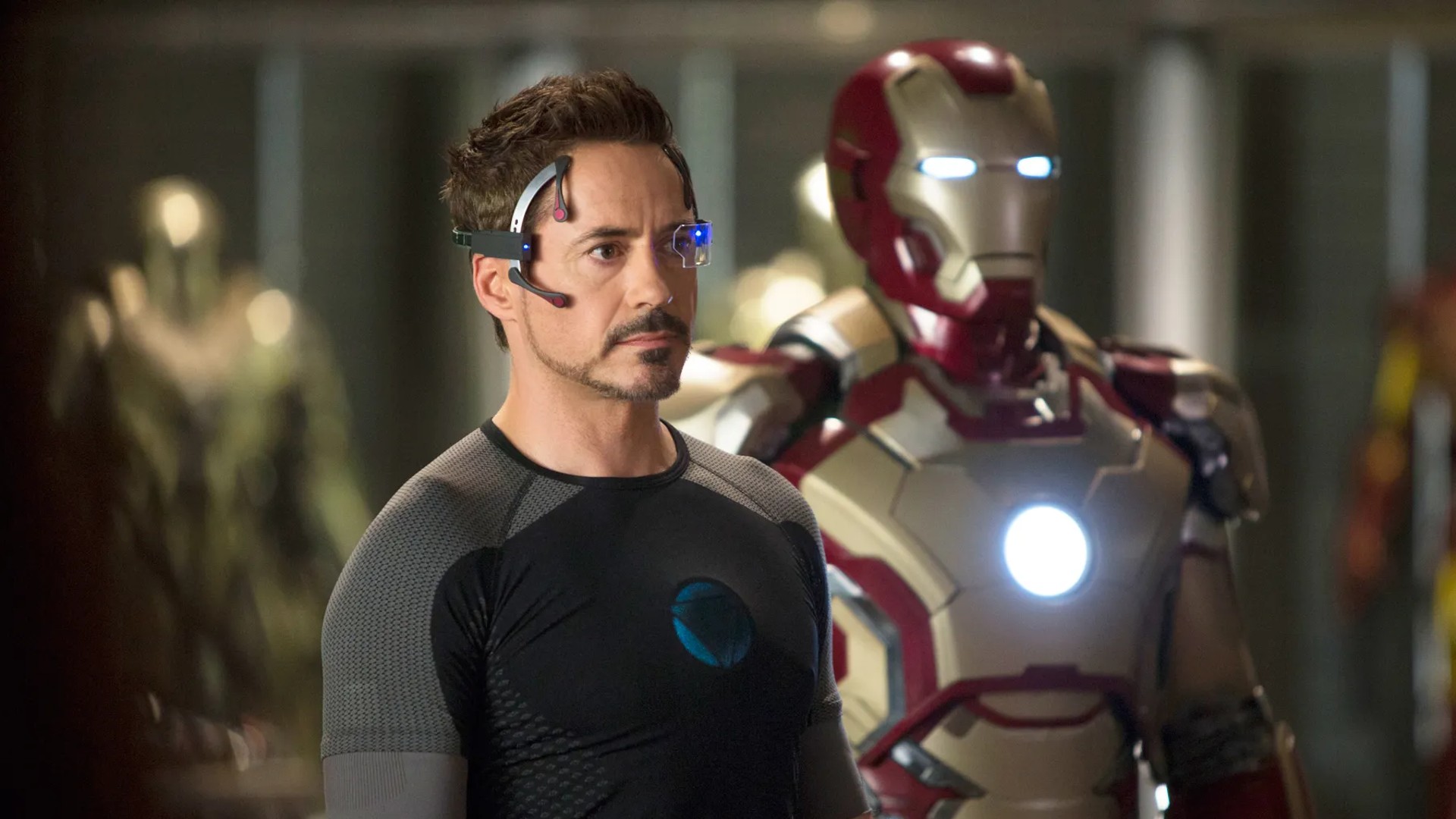 Robert Downey Jr. stands in front of his Iron Man suit in a still from the movie Iron Man 3.